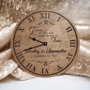 May include: A wooden clock with Roman numerals and a quote about love that reads "Love like ours will stand the test of Time". The clock is personalized with the names "Timothy & Samantha" and the date "September 10, 2018".