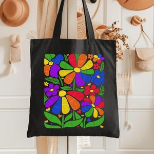 May include: Black tote bag with a colorful rainbow flower design. The flowers are outlined in black and filled with different colors of the rainbow.