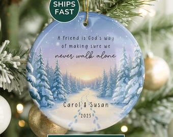 May include: Round ceramic Christmas ornament with a winter scene featuring a snowy path through a forest. The ornament has the text "A friend is God's way of making sure we never walk alone" and personalized names and year.