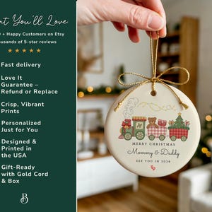 May include: A round Christmas ornament with a train design. The train cars feature a teddy bear, Christmas tree, and gifts. The ornament has the text "Merry Christmas Mommy & Daddy See You in 2026". It is held by a gold cord.