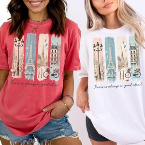 May include: Two women wearing t-shirts with a graphic print of the Eiffel Tower and the text "Paris is always a good idea!" One shirt is watermelon red and the other is white.