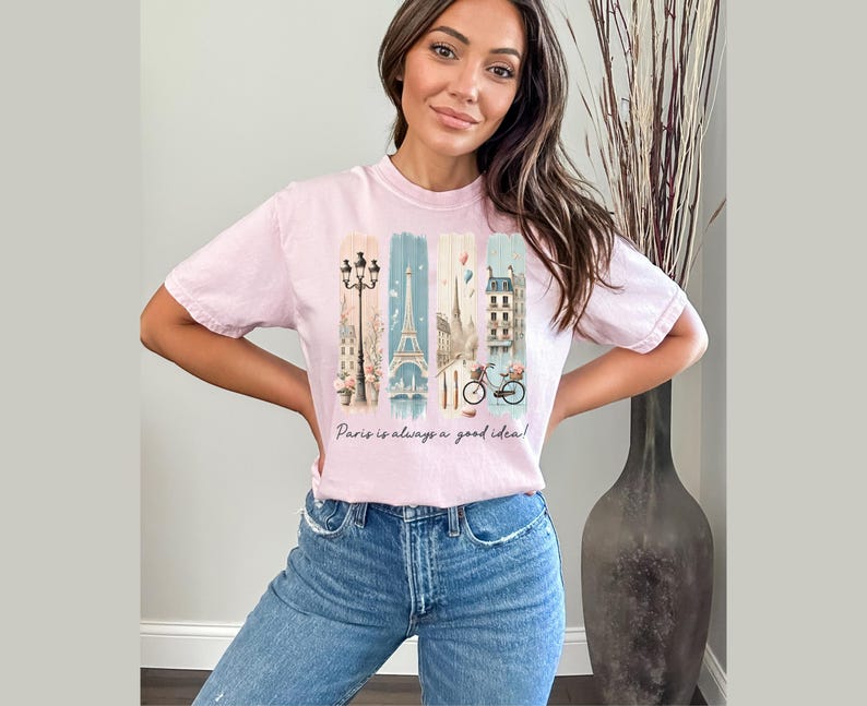 May include: A pink t-shirt with a graphic print of Parisian landmarks, including the Eiffel Tower, a street lamp, and a bicycle. The text "Paris is always a good idea!" is printed below the graphic.