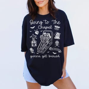 May include: Black t-shirt with a white graphic featuring skeletons in a coffin, a church, and the text "Going to The Chapel gonna get buried." The design includes bats, a rose, and a tombstone.