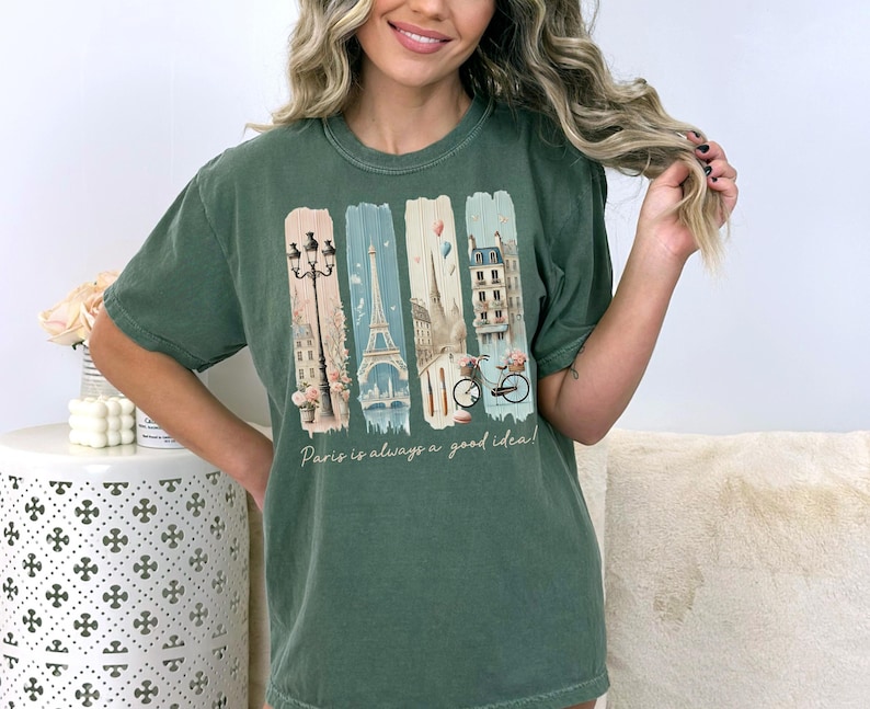 May include: Green t-shirt with a graphic print of Parisian landmarks, including the Eiffel Tower, a street lamp, and a bicycle. The text "Paris is always a good idea" is printed below the graphic.
