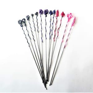 May include: A set of 14 wire stems with twisted wire and colorful wire knots at the top. The knots are in shades of purple, pink, and black.