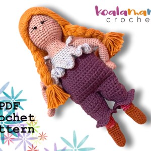 May include: Crochet pattern PDF for a handmade doll with orange hair, a purple skirt, and a white top. The doll is lying on a white background with colorful flower designs.