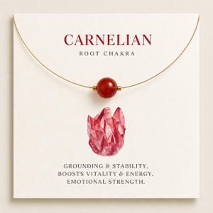 May include: A necklace featuring a single round, polished, deep orange-red carnelian bead on a thin gold-tone wire. The display card reads CARNELIAN ROOT CHAKRA, GROUNDING & STABILITY, BOOSTS VITALITY & ENERGY, EMOTIONAL STRENGTH, with a red crystal illustration.
