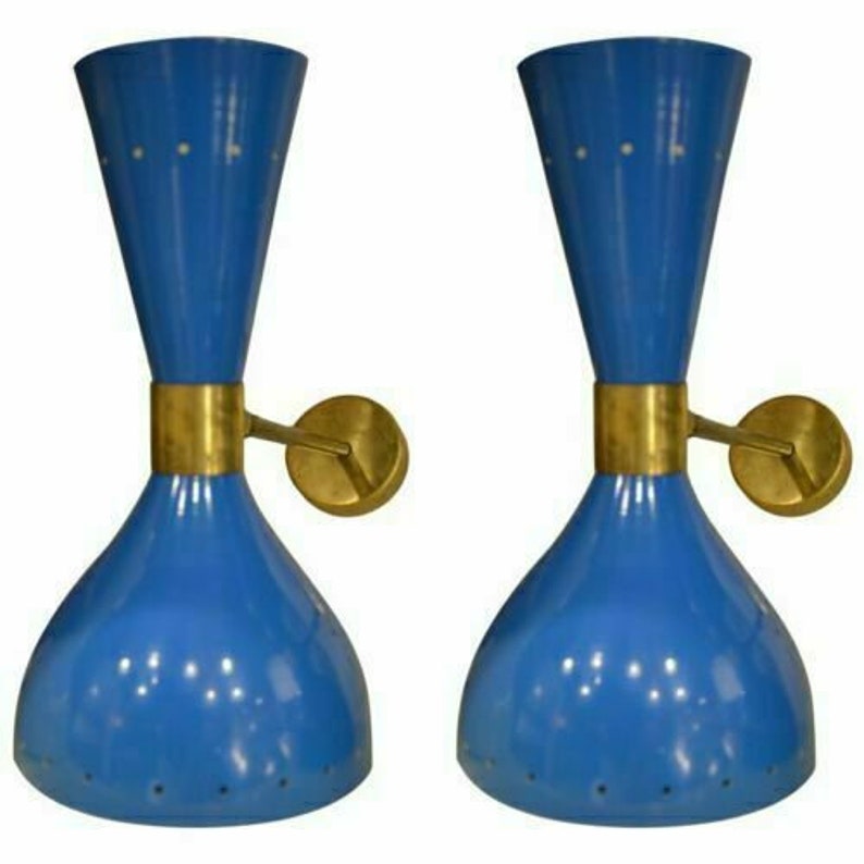 May include: Two blue wall sconces with brass accents. Each sconce has a flared base and a conical top, connected by a brass band. The sconces have small, evenly spaced holes and are mounted on round brass wall plates.