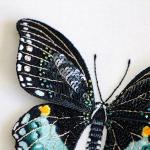 A closer view of the embroidery on the wings of the 3D butterfly. The wings are stitched with thread painting embroidery, sequins, and beads.