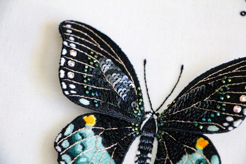 A closer view of the embroidery on the wings of the 3D butterfly. The wings are stitched with thread painting embroidery, sequins, and beads.