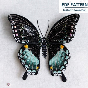 The finished 3D butterfly made from thread painting embroidery and beading, on a white fabric background with a few beads/sequins scattered in the corners and the "PDF Pattern Instant Download" sticker in the right hand corner.