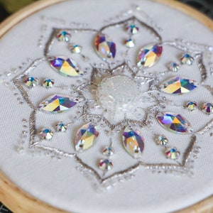 A close up 3/4 view of the finished Crystal Snowflake shows the details of the silver metallic stitching and iridescent crystal beads used in the pattern.