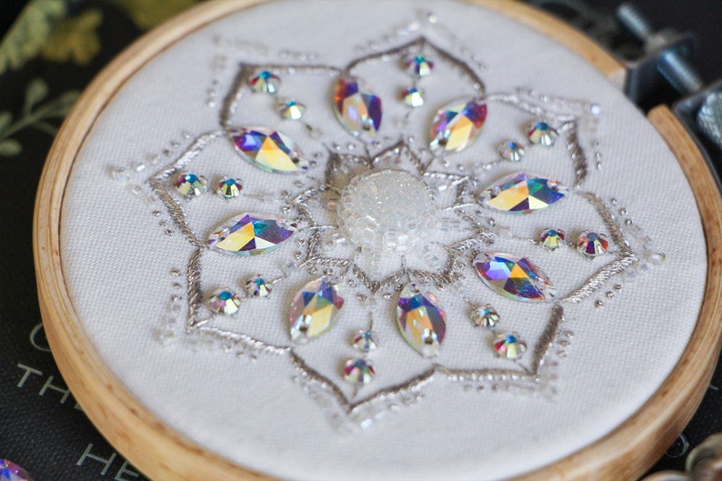 A close up 3/4 view of the finished Crystal Snowflake shows the details of the silver metallic stitching and iridescent crystal beads used in the pattern.
