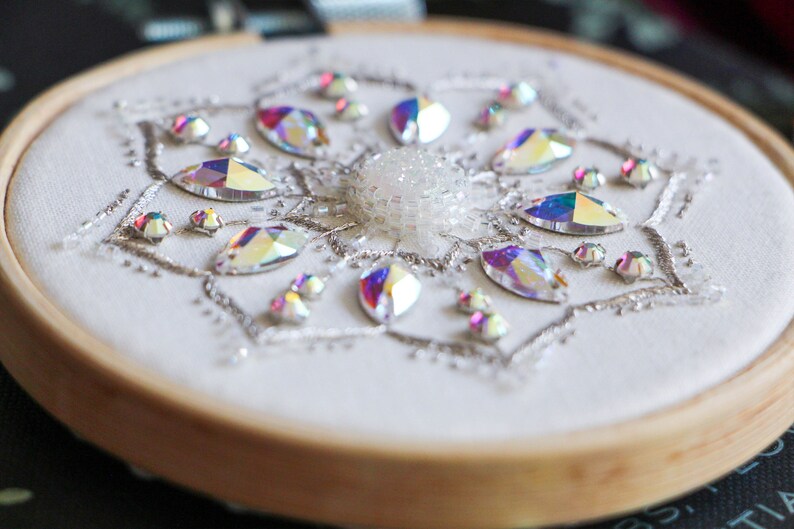 A close up bottom side view of the hoop shows the 3D profile of the beads and central cabochon for the Crystal Snowflake bead embroidery pattern.