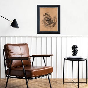 K&ouml;nnte beinhalten: Gerahmte Vintage-Illustration einer sitzenden Figur mit einem nagetierartigen Gesicht, die ein Kleid tr&auml;gt und ein Buch h&auml;lt. Der schwarze Rahmen hat einen strukturierten Rand. Das Bild h&auml;ngt an einer wei&szlig;en Wand &uuml;ber einem braunen Ledersessel und einem schwarzen Beistelltisch.
