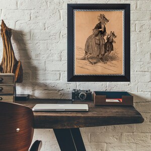 K&ouml;nnte beinhalten: Gerahmter Vintage-Druck mit einer K&auml;nguru-Mutter und ihrem Kind in viktorianischer Kleidung. Der schwarze Rahmen hat ein strukturiertes Muster und einen d&uuml;nnen blau-wei&szlig;en Rand. Das Kunstwerk ist auf einem Holzschreibtisch ausgestellt.