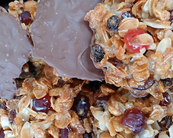May include: Close-up of a crispy, golden brown treat with a variety of toppings, including dried fruit, nuts, and chocolate. The treat is a popular dessert or snack.
