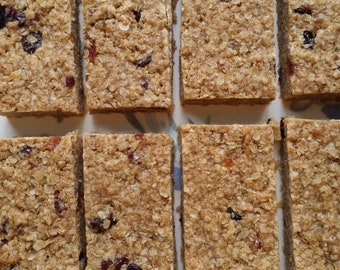 May include: Nine golden brown granola bars with dried fruit and nuts. The bars are arranged in three rows of three.