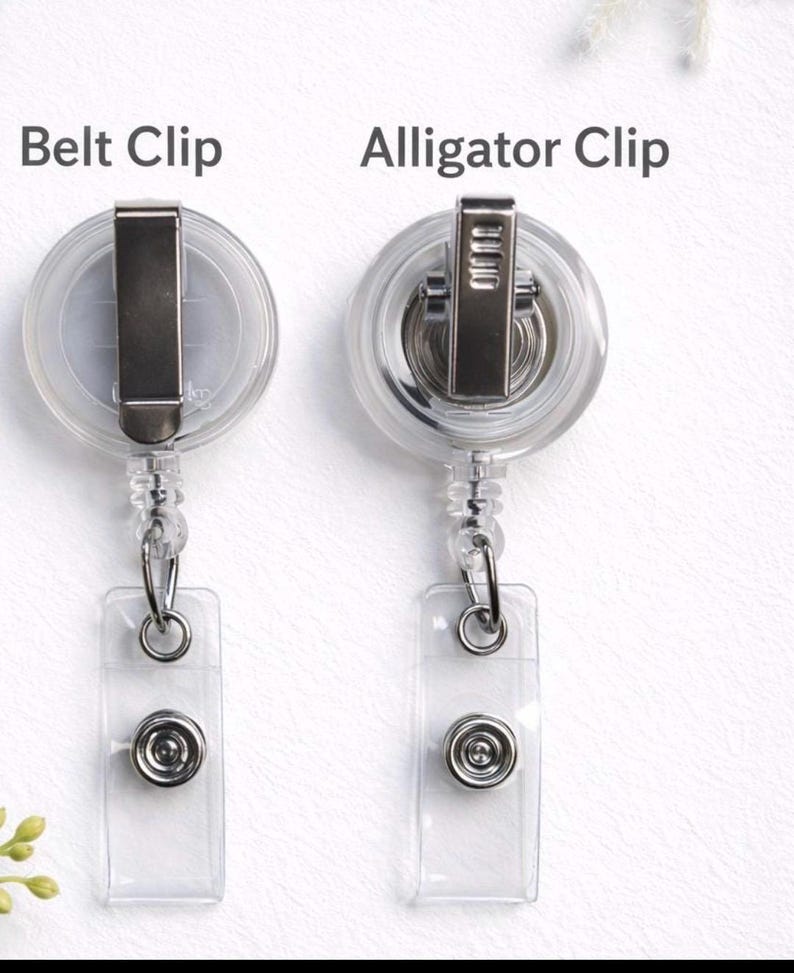 May include: Two retractable badge reels with clear circular housings and transparent vinyl straps. The left reel features a metal belt clip labelled Belt Clip, while the right reel features a metal alligator clip labelled Alligator Clip.