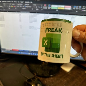 May include: White ceramic mug with green text that reads "Freak X in the Sheets". The mug has a green and white graphic of the letter "X" on it.