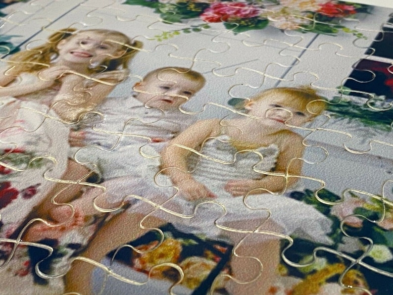 Puede incluir: Un rompecabezas con una foto de tres ni&ntilde;os. Los ni&ntilde;os llevan vestidos blancos y sonr&iacute;en. Las piezas del rompecabezas son visibles alrededor de los bordes de la foto.