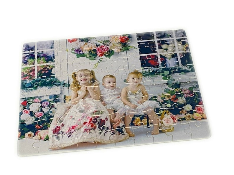 Puede incluir: Tres ni&ntilde;os, dos ni&ntilde;as y un ni&ntilde;o, est&aacute;n sentados en un banco frente a una ventana con flores. Las ni&ntilde;as llevan vestidos blancos con estampados florales. El ni&ntilde;o lleva una camisa blanca. El fondo es una pared blanca con una ventana y flores.
