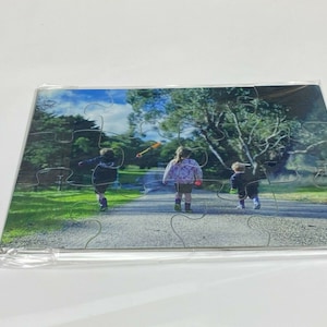 Puede incluir: Un rompecabezas de fotos con tres ni&ntilde;os caminando por un sendero en un parque. Los ni&ntilde;os visten ropa informal y caminan en fila. El rompecabezas est&aacute; hecho de cart&oacute;n y tiene un acabado brillante.