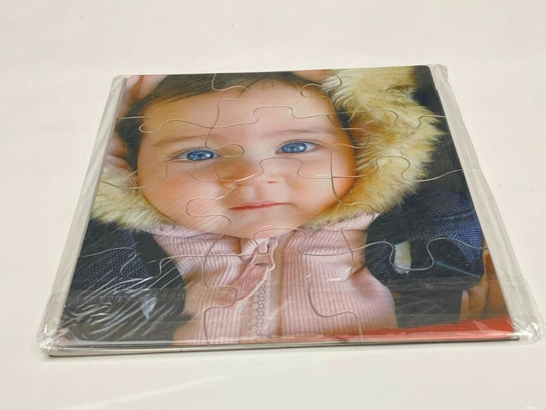 Puede incluir: Primer plano de un beb&eacute; que lleva una chaqueta rosa y blanca con capucha de piel. El beb&eacute; tiene ojos azules y mira a la c&aacute;mara.