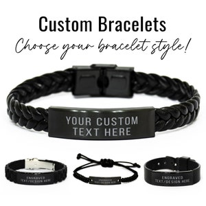 May include: Three black bracelets with a metal plate for engraving. The top bracelet is a braided leather bracelet with a metal clasp. The middle bracelet is a black braided cord bracelet with a metal clasp. The bottom bracelet is a black metal bracelet with a metal clasp. The metal plates on all three bracelets have the text "ENGRAVED TEXT/DESIGN HERE".