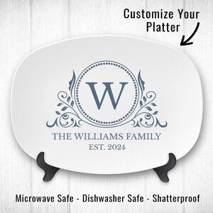 May include: White oval serving platter with a blue monogram design. The monogram features a large "W" surrounded by a circle of dots and a decorative floral design. The text "THE WILLIAMS FAMILY EST. 2024" is printed below the monogram.