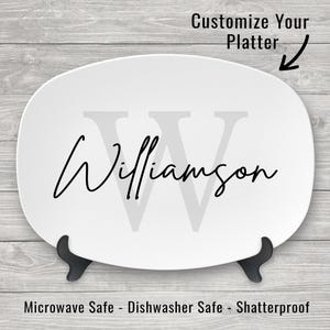May include: White oval serving platter with a gray letter "W" and the name "Williamson" written in black cursive. The platter is on a stand and has the text "Customize Your Platter" and "Microwave Safe - Dishwasher Safe - Shatterproof" printed on the bottom.
