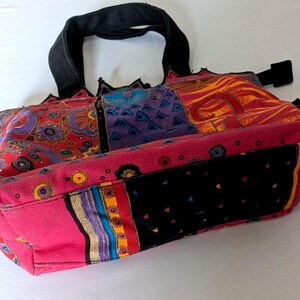 Puede incluir: Un bolso tipo tote con dise&ntilde;o de patchwork que presenta paneles de tela en colores rojo, morado, naranja y negro vibrantes. El bolso incluye asas negras, una base negra con peque&ntilde;os tri&aacute;ngulos coloridos y varios patrones florales y geom&eacute;tricos.