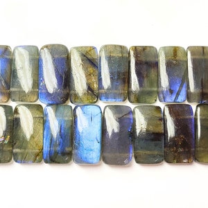 May include: A strand of 18 rectangular labradorite gemstone beads with a blue iridescent sheen. The beads are strung on a wire with a black tassel at each end.