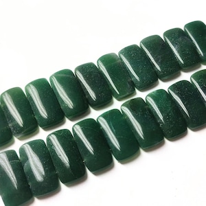 Könnte beinhalten: Eine Strähne aus 18 rechteckigen grünen Jadeperlen mit silbernen Quasten an jedem Ende.