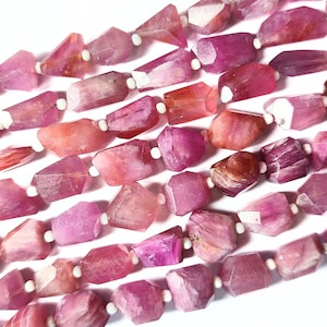 Op de afbeelding: Een streng roze en witte edelsteen kralen. De kralen zijn gefacetteerd en hebben een ruwe, natuurlijke textuur.