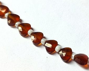 May include: A strand of brown heart-shaped gemstone beads with white spacer beads.