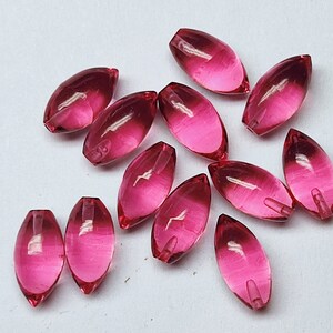 May include: A group of pink glass beads in an oval shape. The beads are translucent and have a slight shimmer.