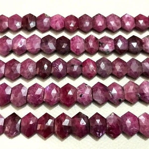May include: A strand of faceted ruby beads, each bead is a deep pink color and has a hexagonal shape. The beads are strung together on a clear thread.