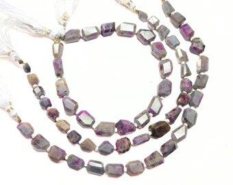May include: Three strands of gemstone beads with a mix of gray, purple, and brown tones. The beads have an irregular, faceted shape. White tassels are attached to the ends of the strands, creating a layered effect.