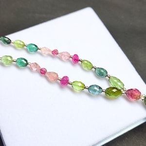 Könnte beinhalten: Eine mehrfarbige Edelstein-Halskette mit grünen, blauen und rosa ovalen Perlen. Die Halskette hat einen silbernen Verschluss und einen großen, ovalen Anhänger aus grünem Edelstein.