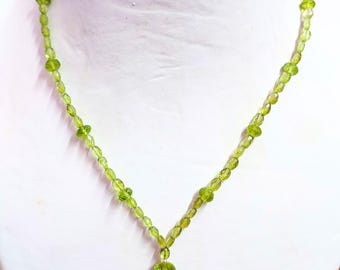 May include: A green peridot gemstone necklace with a pendant. The necklace is made of faceted beads and is strung on a silver chain.