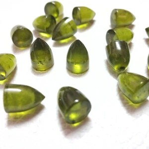Puede incluir: Una colecci&oacute;n de 18 cabujones de piedras preciosas verdes en forma de l&aacute;grima. Las piedras est&aacute;n facetadas y tienen un acabado liso y pulido.
