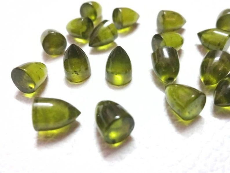 Puede incluir: Una colecci&oacute;n de 18 cabujones de piedras preciosas verdes en forma de l&aacute;grima. Las piedras est&aacute;n facetadas y tienen un acabado liso y pulido.