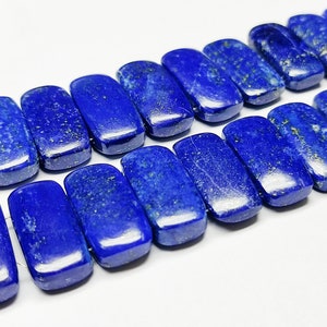 May include: A strand of dark blue lapis lazuli gemstone beads. The beads are rectangular and have a smooth, polished finish.
