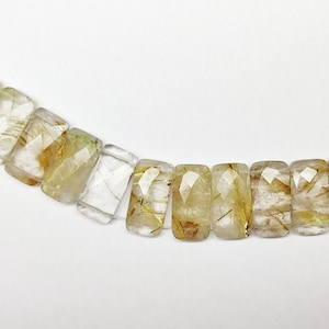 May include: A strand of faceted, rectangular, clear quartz beads with gold inclusions. The beads are strung on a clear elastic cord.