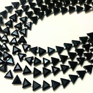 Könnte beinhalten: Eine Halskette aus schwarzen Onyx-Dreiecksperlen mit mehreren Strängen. Die Perlen sind facettiert und hochglanzpoliert.