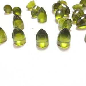 Puede incluir: Una colecci&oacute;n de cabochones de piedras preciosas verdes, cada uno con una parte superior puntiaguda y una base redondeada. Las piedras son transl&uacute;cidas y tienen un ligero brillo.