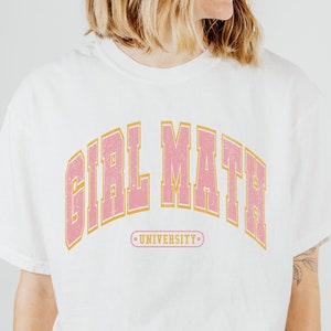 Puede incluir: Camiseta blanca con un gráfico rosa y dorado que dice "Girl Math University".