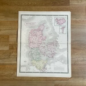 Könnte beinhalten: Eine antike Karte von Dänemark mit detaillierter Kartografie in Rosa, Grün und Gelb. Inset-Karten von Island und den Färöer-Inseln sind enthalten. Das Wort "DENMARK" ist oben auf der Karte aufgedruckt.