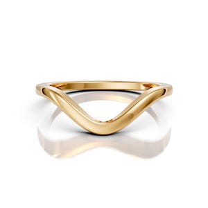 May include: A gold-colored ring with a curved, V-shaped design. The ring is smooth and polished, reflecting light. The band is a continuous loop, with a simple, elegant style. The ring is set against a white background.